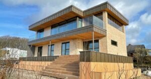 Modern two-story house with large glass balcony.