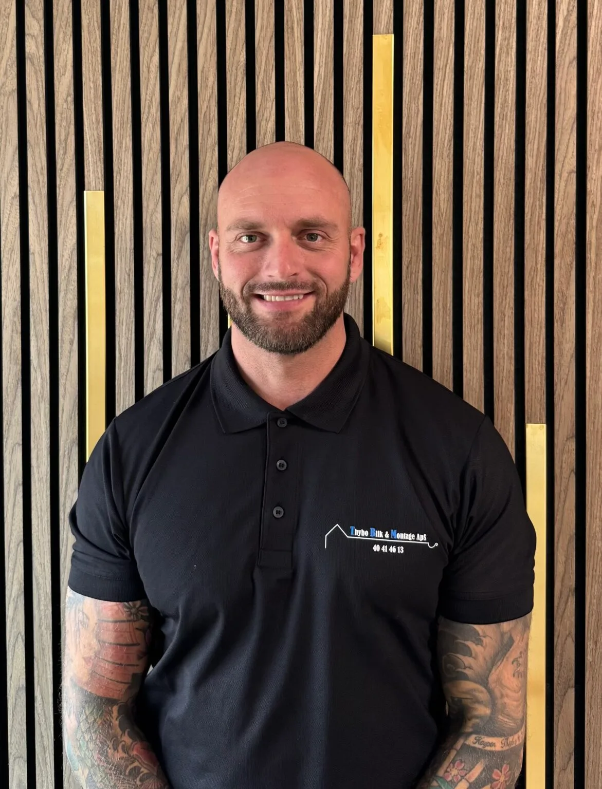 Man smiling in black polo shirt with logo